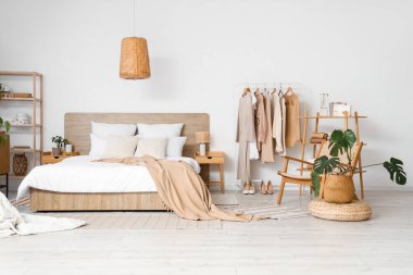 Modern konforlu yatak odası ve kadın giysileriyle dolu raflar.