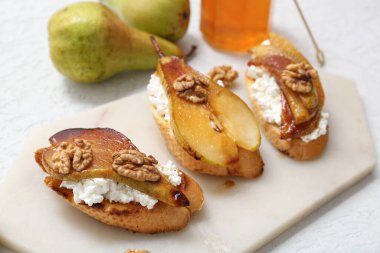 Beyaz arka planda ricotta peynirli ve cevizli armut bruschetta, yakın plan.