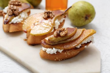 Beyaz arka planda ricotta peynirli ve cevizli armut bruschetta, yakın plan.