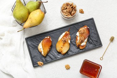 Beyaz arka planda armut bruschetta, ricotta peyniri, ceviz ve cam bal kasesi.