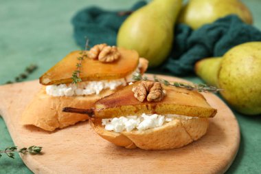 Armut bruschetta tahtası ricotta peyniri, ceviz ve kekik ile yeşil arka planda, yakın plan