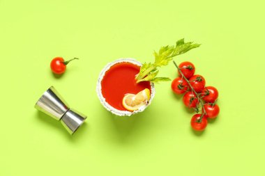 Kereviz, domates, limon dilimi ve açık yeşil arka planda ölçü kabıyla bir bardak Bloody Mary.