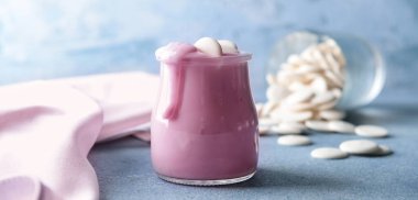 Açık mavi arka planda bir kavanoz lezzetli yoğurt.