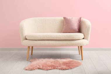 Pembe duvarın yanında minderli ve kürklü kanepe.