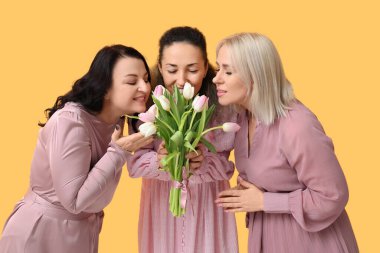 Sarı arka planda bir buket güzel lalesi olan olgun kadınlar. Uluslararası Kadınlar Günü