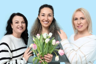 Mavi arka planda bir buket güzel lalesi olan olgun kadınlar. Uluslararası Kadınlar Günü