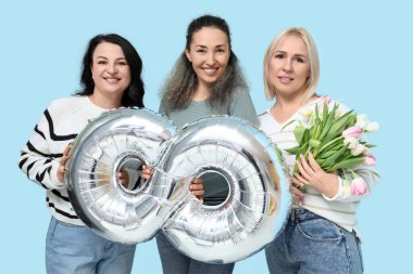 Şekil 8 şeklinde gümüş hava balonu olan olgun kadınlar ve mavi arka planda güzel laleler. Uluslararası Kadınlar Günü