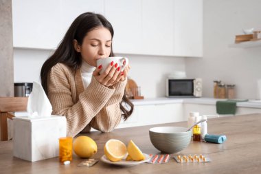 Genç bayan mutfakta sıcak çay içiyor.