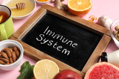 IMMUNE SİSTEM ve pembe arka planda farklı sağlıklı yiyeceklere sahip tebeşir tahtası