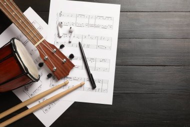 Koyu ahşap arka planda müzik kağıtları, müzik aletleri ve kulaklıkları olan kompozisyon