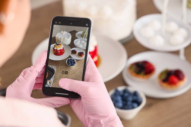 Kadın pastacı, mutfakta kek fotoğrafı çekiyor, yakın plan.