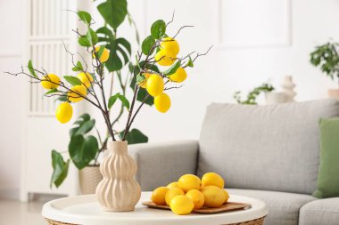 Oturma odasındaki masada ağaç dalları ve limonlu vazo.