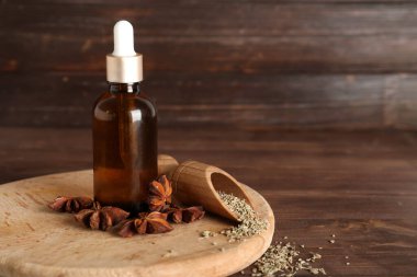 Yağ şişesi, anasonlu yıldızlar, kurumuş tohumlar ve ahşap arka planda kepçe