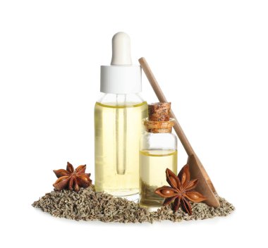 İçinde anason yıldızları, ahşap kaşık ve beyaz arka planda kurumuş tohumlar olan gerekli yağ şişeleri.