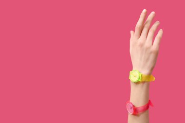 Pembe arka planda kol saatleri olan bir kadın el.