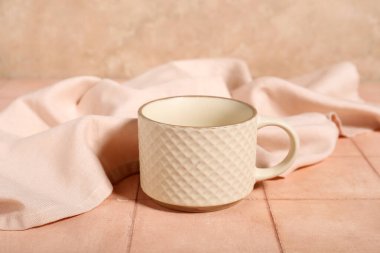 Beyaz seramik kupa, bej döşeme masasında kumaş.