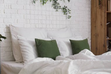 Yatak odasında beyaz ve yeşil yastıklı