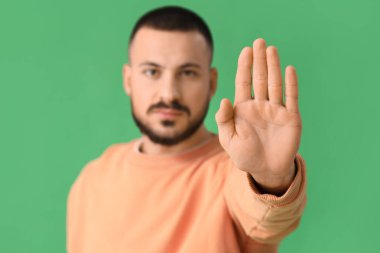 Yeşil arka planda DUR hareketi gösteren genç adam, yakın plan. Kural kavramı