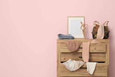 Tuvalet, oturma odasındaki pembe duvarın yanında dağınık giysilerle.