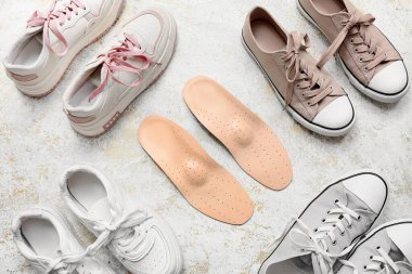 Açık arkaplanda ortopedik tabanlı farklı ayakkabılar.