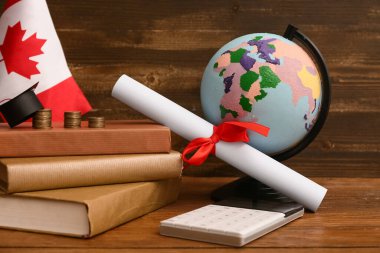 Kitaplı sikkeler, diploma, dünya ve Kanada bayrağı ahşap masada, yakın plan. Öğrenci kredisi kavramı