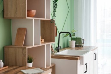 Lavabosu, beyaz tezgahları ve rafları olan şık bir mutfak.