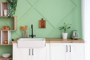 Lavabosu, beyaz tezgahları ve rafları olan şık bir mutfak.