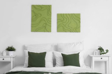 Şık bir yatak odası, rahat bir yatak odası, komodin ve güzel tablolar.