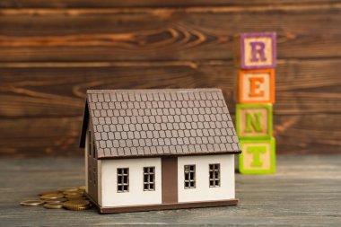 Kelime RENT ile oyuncak ev ve ahşap arka planda paralar