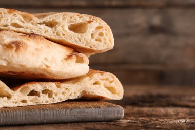 Ahşap arka planda lezzetli lavaş parçaları yığını olan tahta.