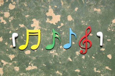 Kulaklıklı kompozisyon ve yeşil grunge arkaplan üzerine dekoratif müzik notaları