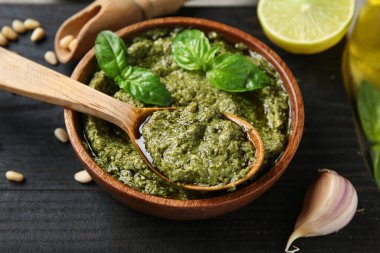 Bir kase lezzetli pesto sosu, kaşık, fesleğen yaprağı ve sarımsak, yakın plan.