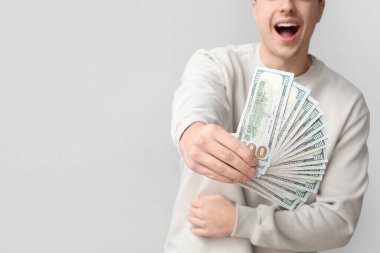 Arka planda dolar banknotları olan mutlu genç adam, yakın plan.