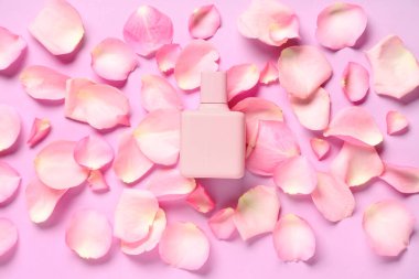 Bir şişe parfüm ve leylak arkaplanda pembe gül yaprakları.