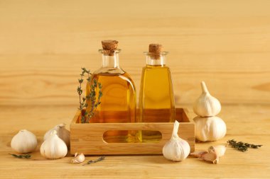 Tahta zemin üzerinde kekik olan bir şişe taze sarımsak yağı.