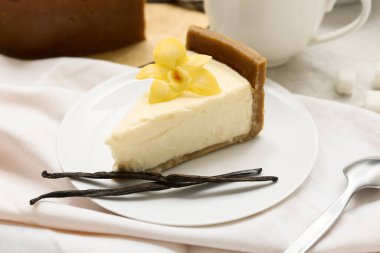 Vanilya çiçekli bir tabak tatlı cheesecake ve beyaz arka planda çubuklar.
