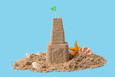 Güzel kumdan kale, mavi arka planda deniz kabukları