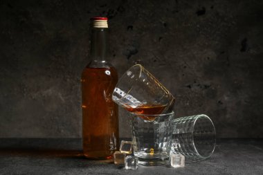 Gri arkaplanda soğuk rom olan şişe ve cam.