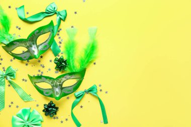 Sarı arka planda tüyleri ve fiyonkları olan güzel yeşil karnaval maskeleri