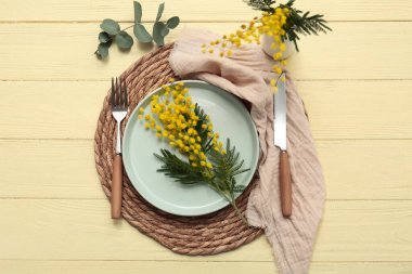 Mimoza çiçekleri ve sarı ahşap arka planda okaliptüs olan güzel bir masa.