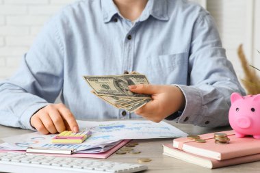 Dolar banknotları olan bir iş kadını masada hesap makinesi kullanıyor, yakın plan. Mali Sağlık Ayı