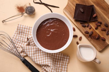 Lezzetli sıcak çikolatalı kase, çırpı ve bej arka planda bir kavanoz süt. Üst görünüm