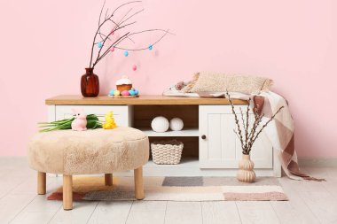 Klozette Paskalya süsleri ve pembe duvarın yanındaki puf çiçekleriyle oturma odasının içinde.