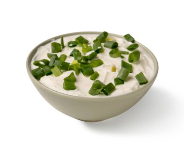 Beyaz arka planda yeşil soğanlı bir kase lezzetli ekşi krema