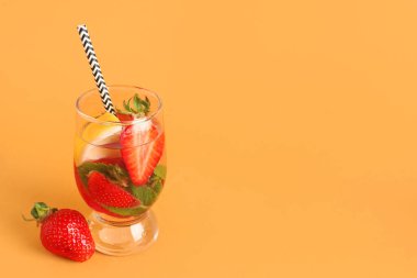 Turuncu arka planda çilekli ve limonlu bir bardak taze limonata.