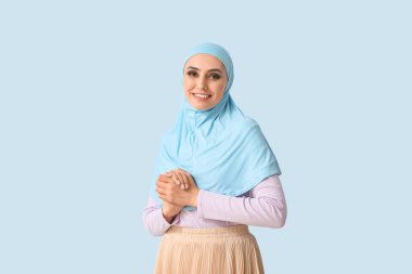 Young Muslim woman on blue background. Islamic New Year celebration