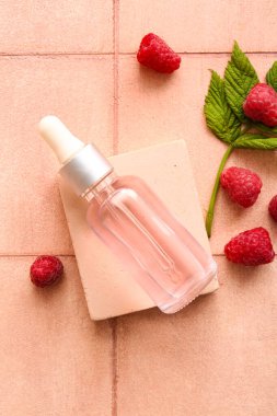 Dekoratif podyum, pembe fayans zemininde bir şişe kozmetik ahududu yağı.