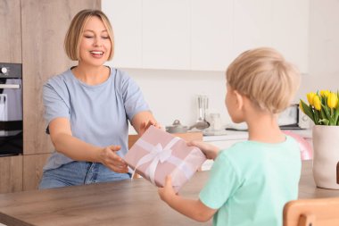 Mutfaktaki küçük oğlundan hediye alan mutlu bir anne. Uluslararası Kadınlar Günü