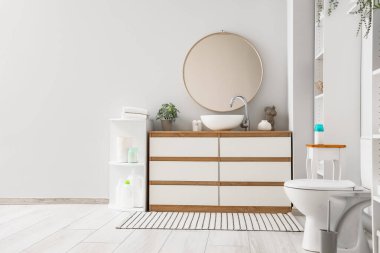 Modern klozet, lavabosu ve aynası olan çekmeceler tuvalette beyaz duvarın yanında.