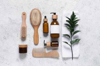 Şampuan şişeleri, saç fırçaları ve beyaz grunge arka planda yeşil dal içeren kompozisyon